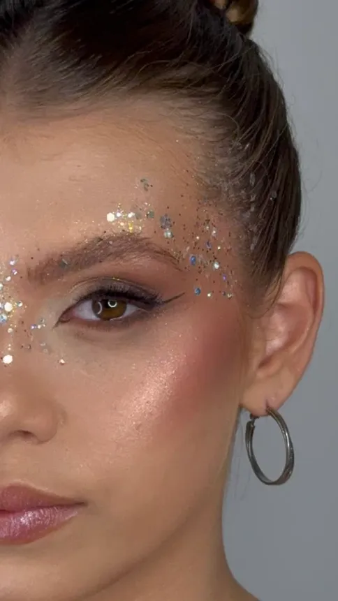 Maquiagem artística com glitter prateado ao redor dos olhos